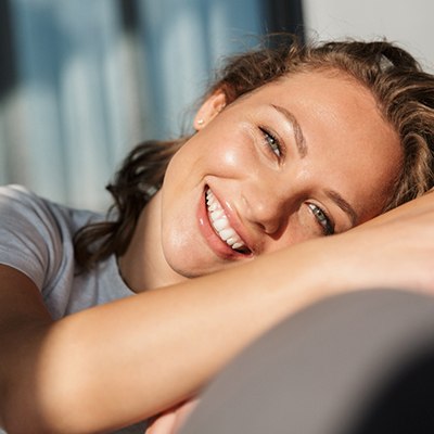 Woman leaning on chair smiling in sunshine