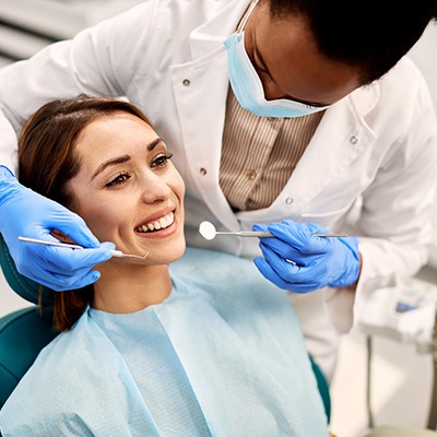 Dentist leaning over to begin a woman’s exam
