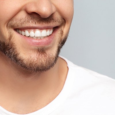 Nose-to-shoulder view of man in white t-shirt smiling