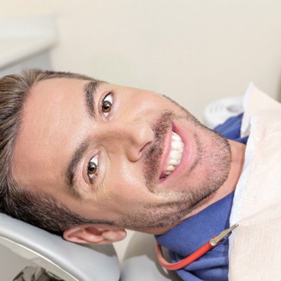 Older man laying back in dental chair smiling