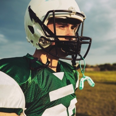 Teen wearing football uniform with athletic mouthguard