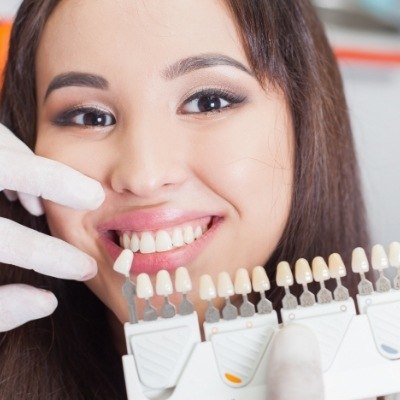 Woman's smile compared with dental bonding color chart