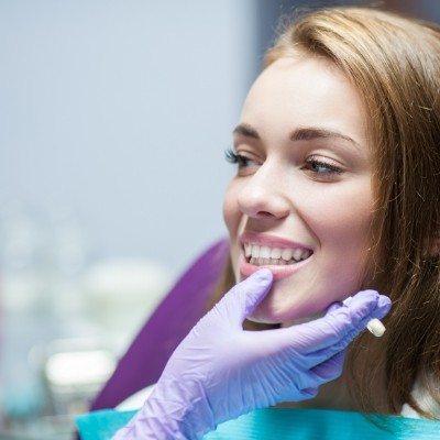 Dentist examining patient's smile after dental crown restoration
