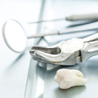 Tooth, forceps, and other dental tools lying on table
