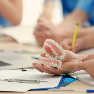 Dentist using smile model to explain why dental implant fail