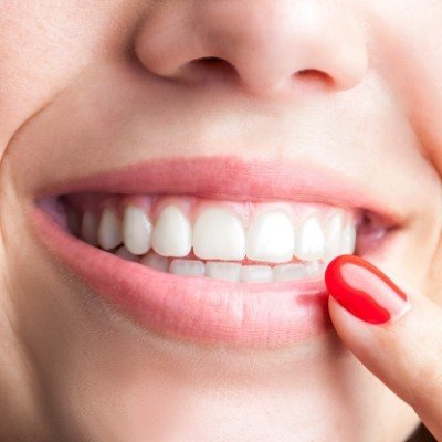 Woman pointing to healthy smile after periodontal disease treatment