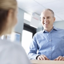 Man talking with dental team member at front desk