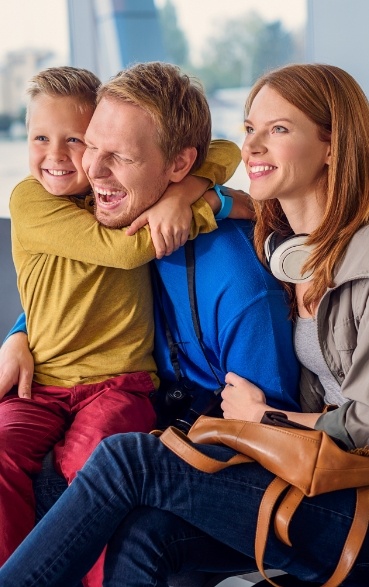 Mother father and young child smiling while sitting outdoors