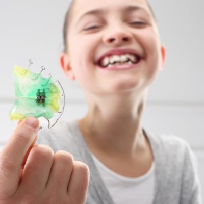 Young woman smiling and holding a retainer