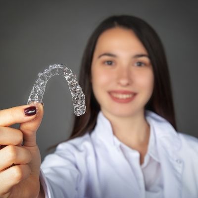 Woman holding an Invisalign clear braces tray