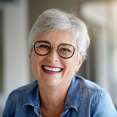 Women with black glasses and denim shirt smiling