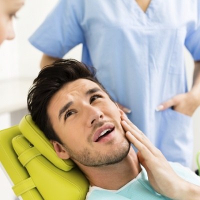 Man in need of T M J treatment holding jaw in pain