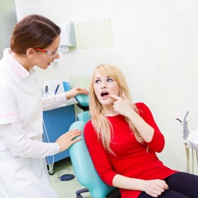 Woman talking to dentist and pointing to jaw before wisdom tooth extractions