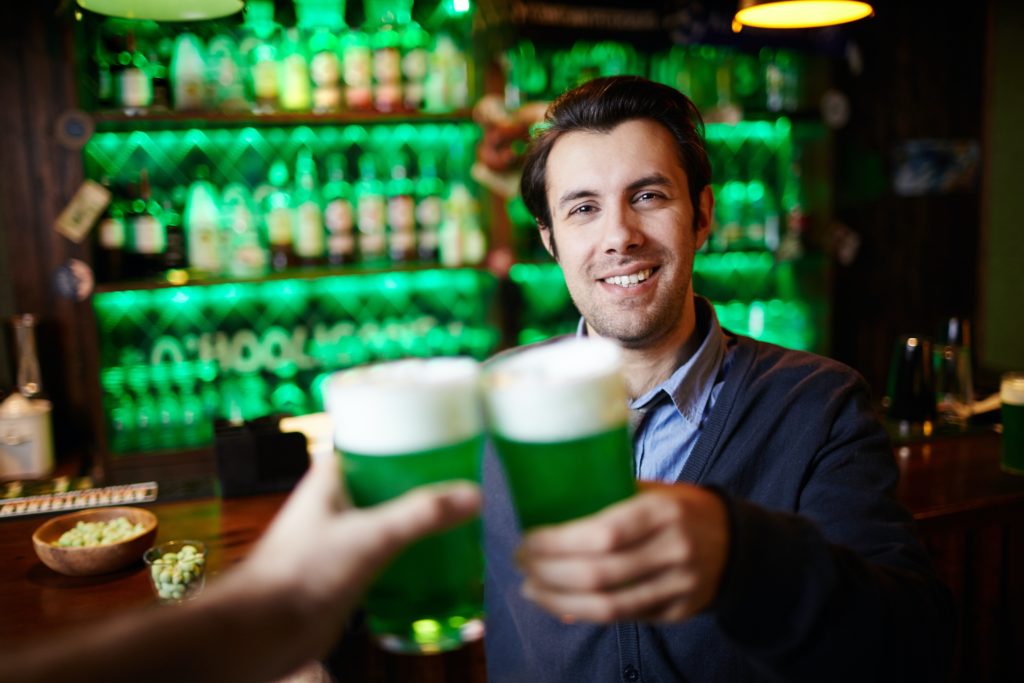 people clinking together glasses of green beer