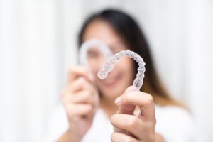 Woman holding up her Invisalign clear aligners